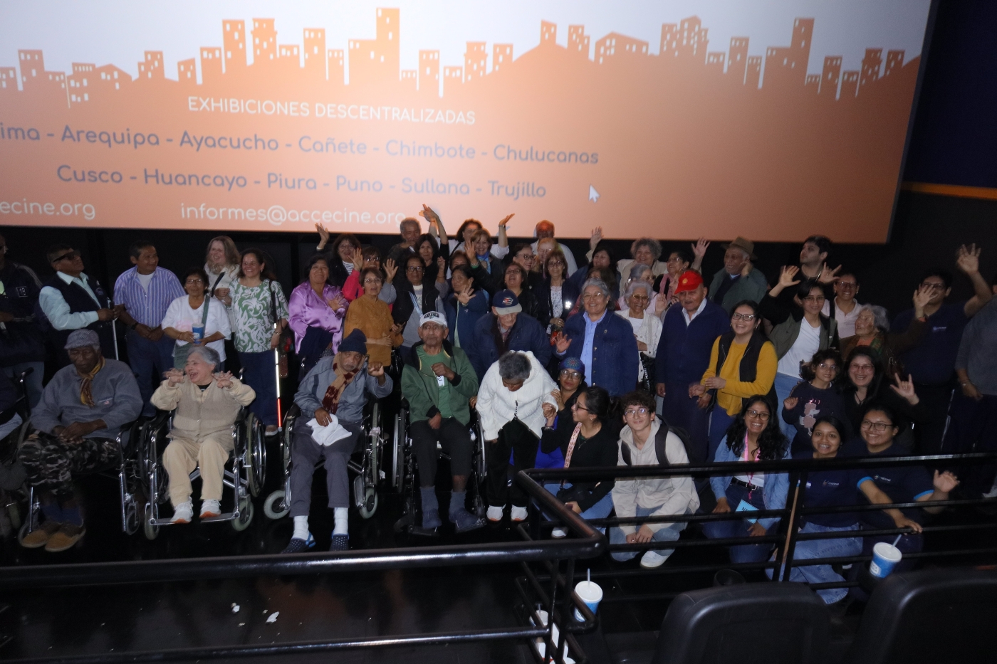 Personas con discapacidad, en una sala de cine, posan para la foto delante de una pantalla con el diseño del Festival Accecine.